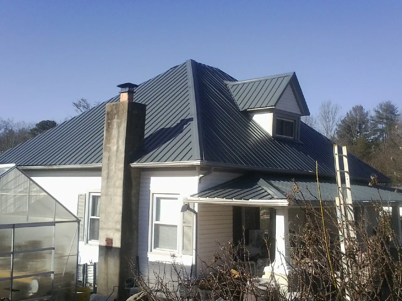 Dark blue standing seam metal roof on a white farmhouse with dormer — Slate & Tile Roof Repair by Roofing Brothers in Woodbourne