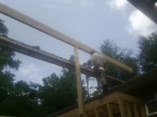 Carpenter setting a ridge beam over a new addition frame — Ice Dam Removal by Roofing Brothers in Woodbourne