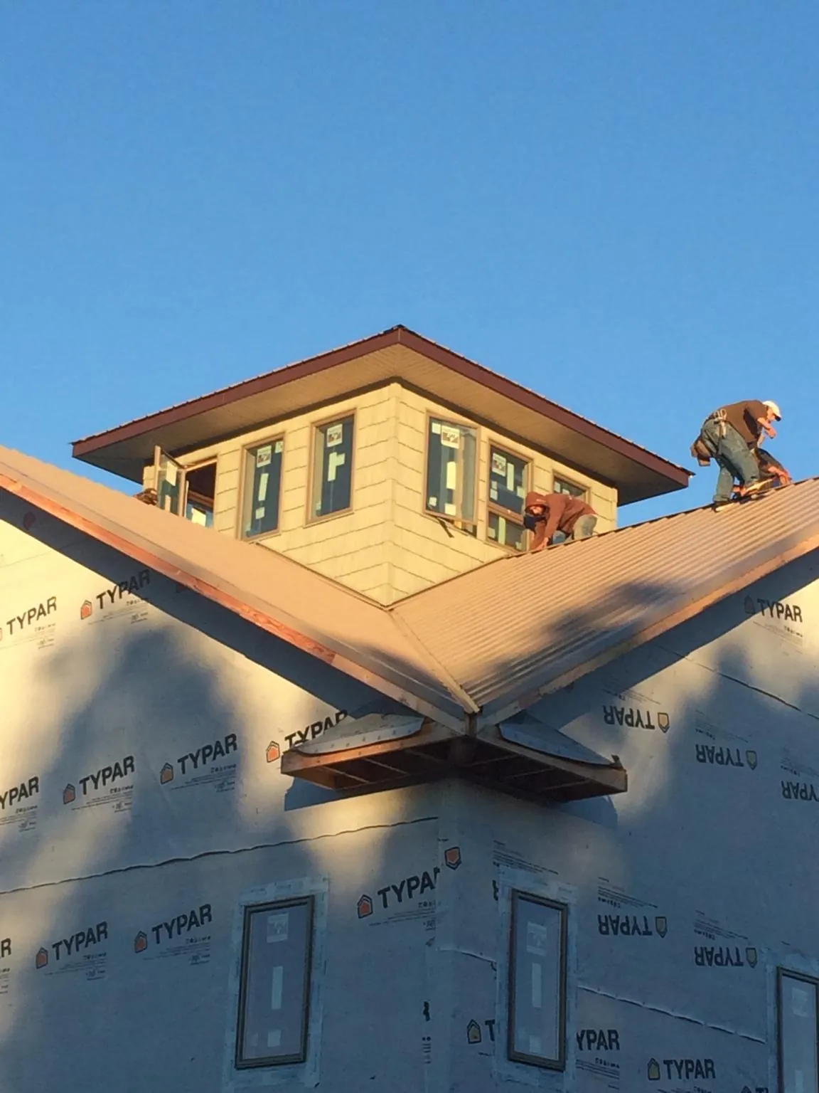 Roofers working around a rooftop cupola on a new metal roof at sunset — Roof Waterproofing in Woodbourne by Roofing Brothers